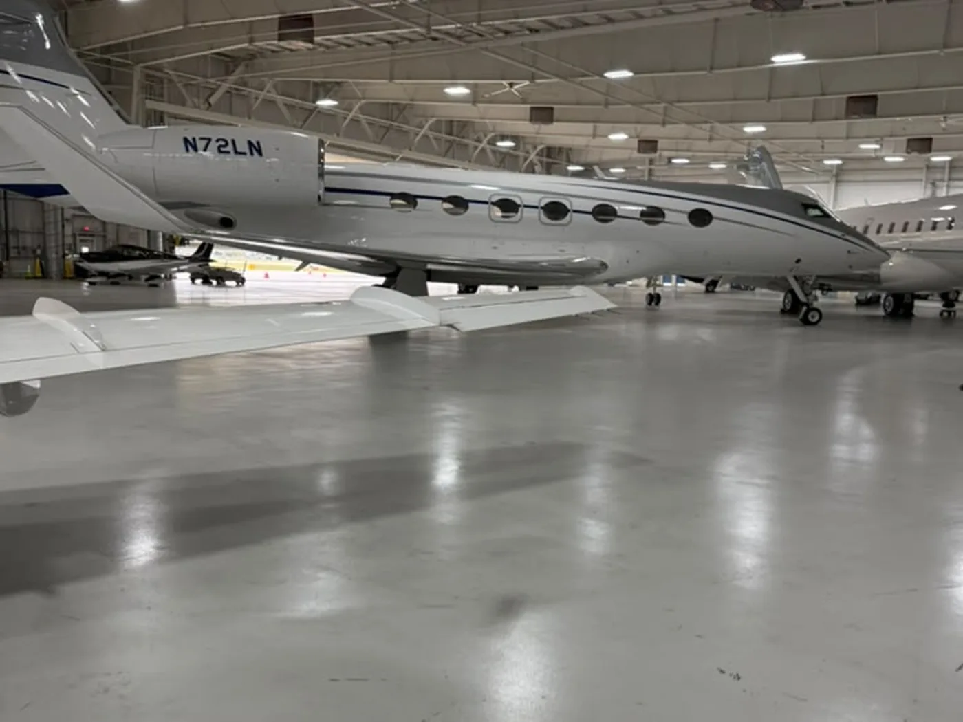 Polished aircraft hangar floor beside a private jet after an Excel Facility Maintenance floor care service