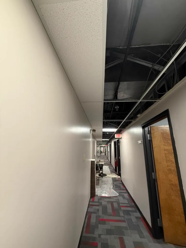 Corridor with ceiling grid opened up during an interior maintenance and build-out phase