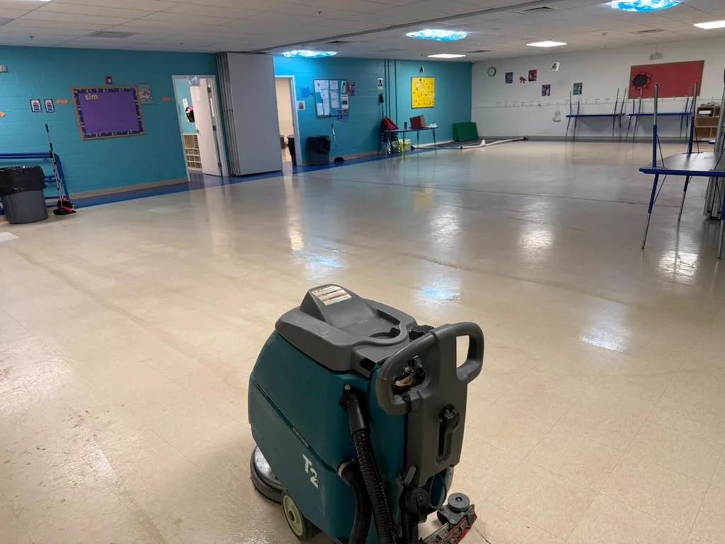 Excel Facility floor scrubber mid-pass across a freshly burnished school cafeteria floor